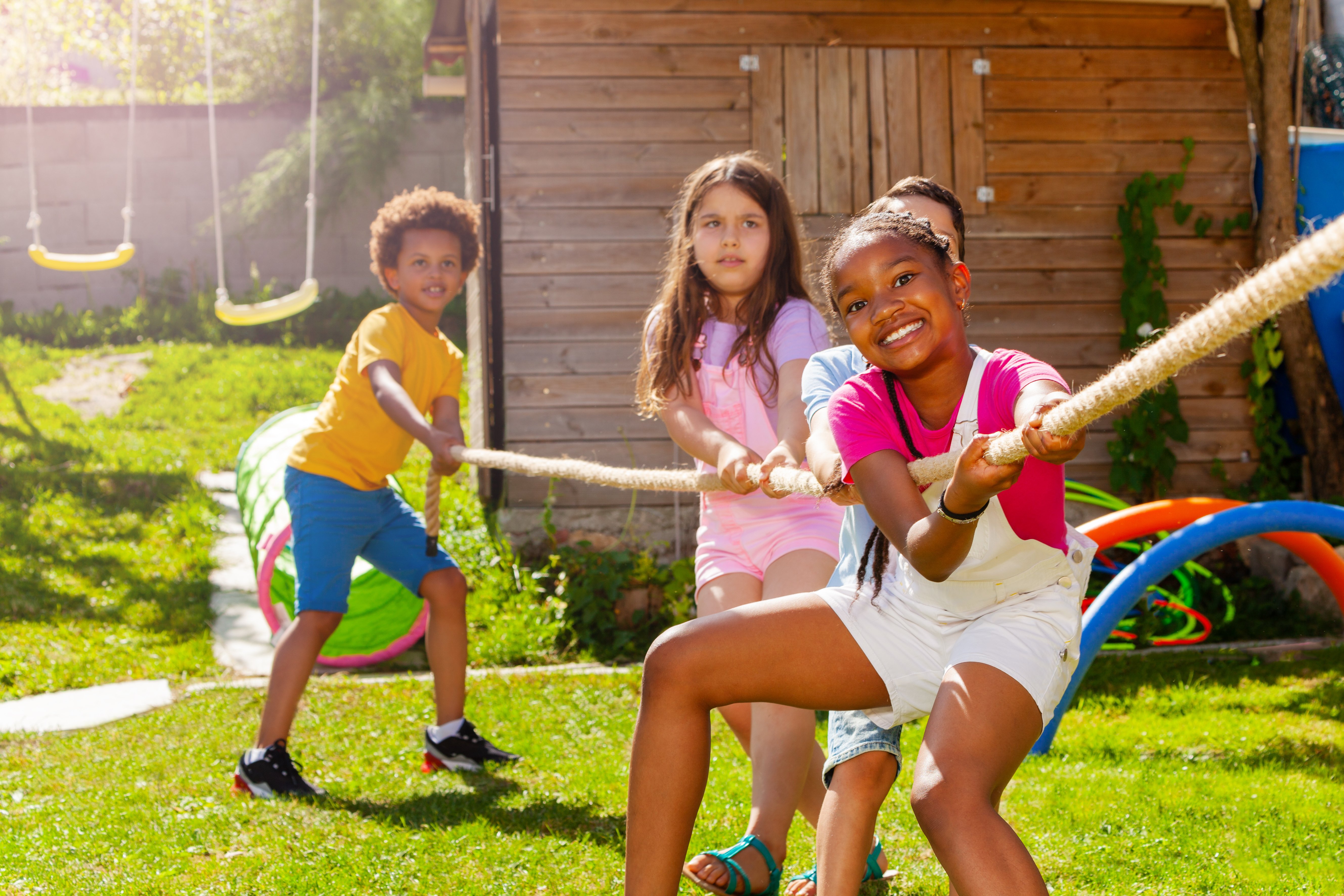 three kids playing tug of war outside at summer camp