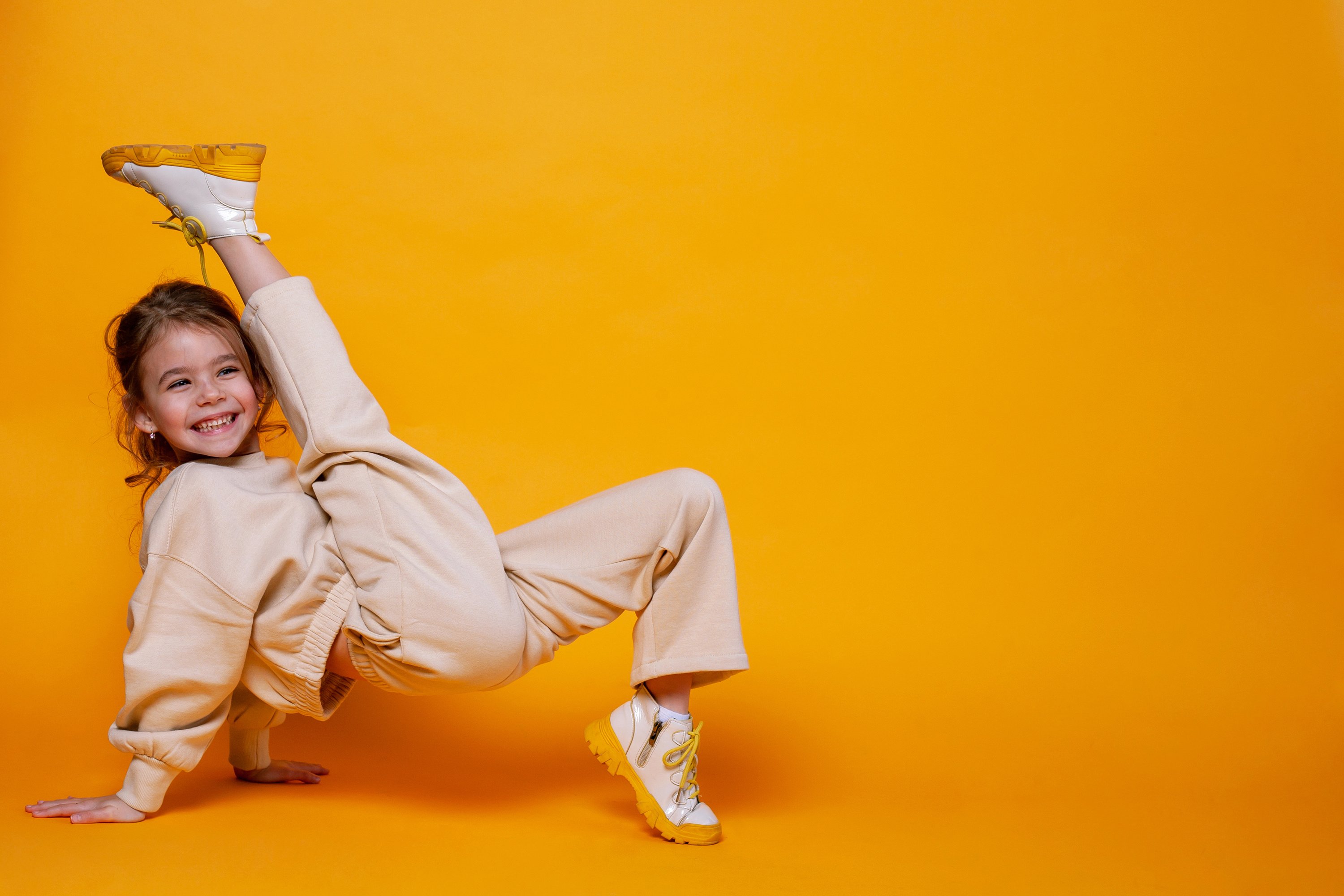 young girl break dancing with orange background 