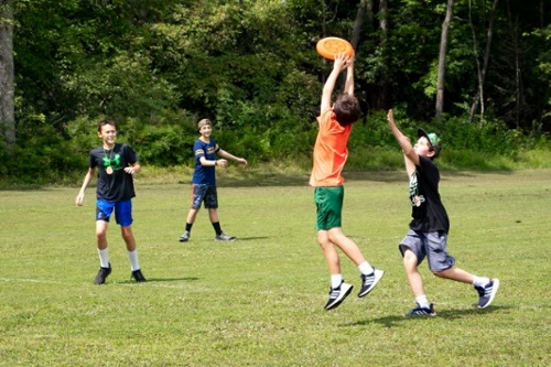 Boys playing together at summer camp throwing a frisbee