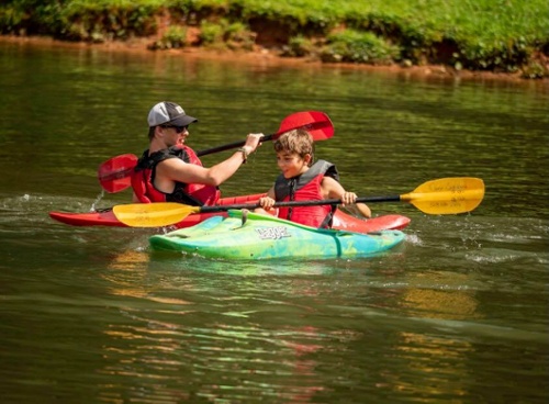 a young boy and a camp counselor learning how to kayak at summer camp