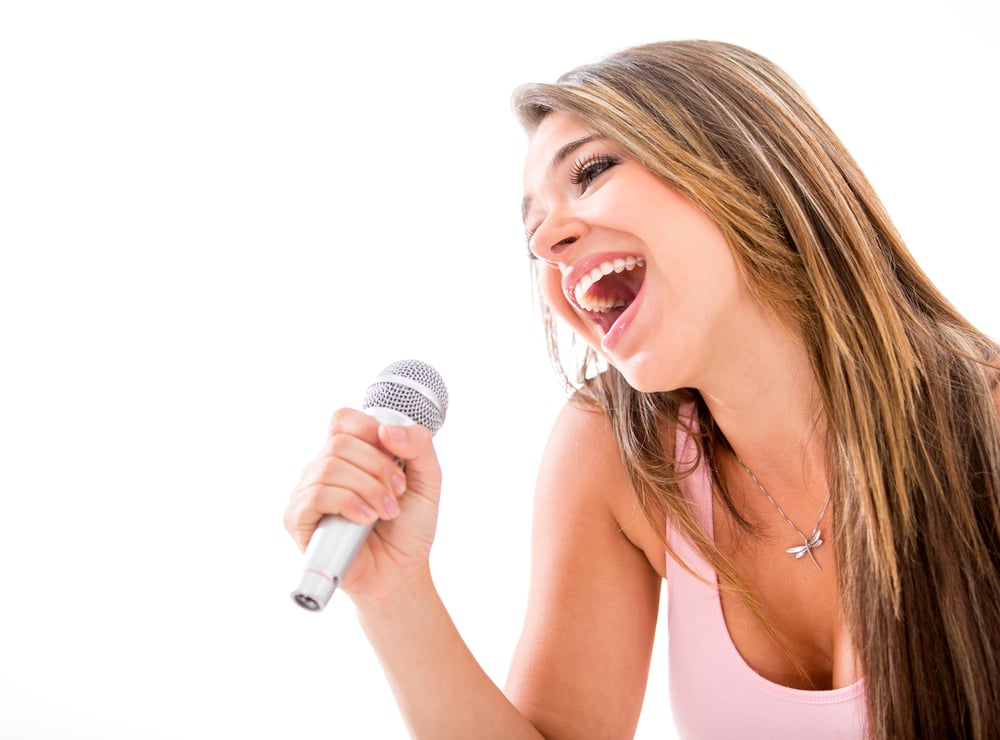 Woman karaoke singing with a microphone - isolated over a white background