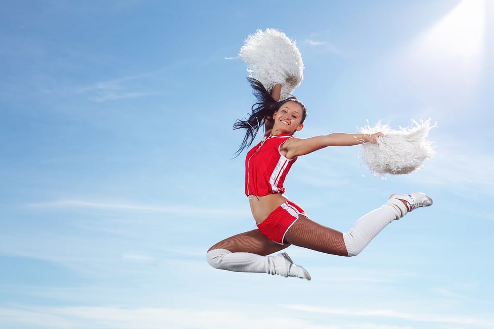 Young beautiful female cheerleader in uniform jumping high-1