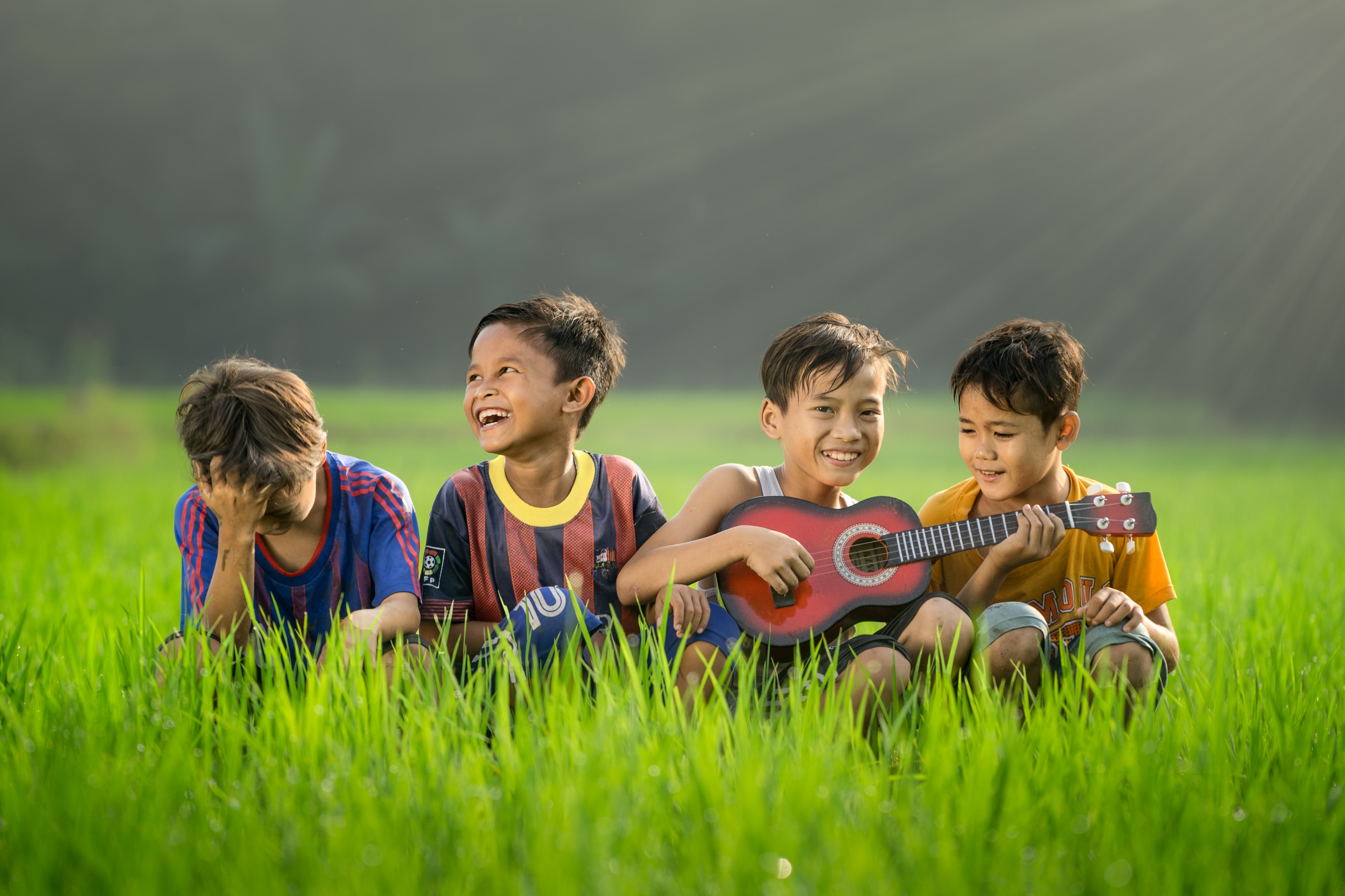 kids sitting in a field with a guitar