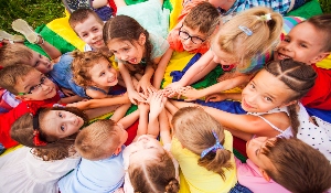 Kids at summer camp huddled together with hands in center