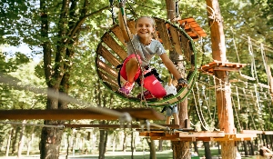 girl playing on an outdoor obstacle course in the woods 