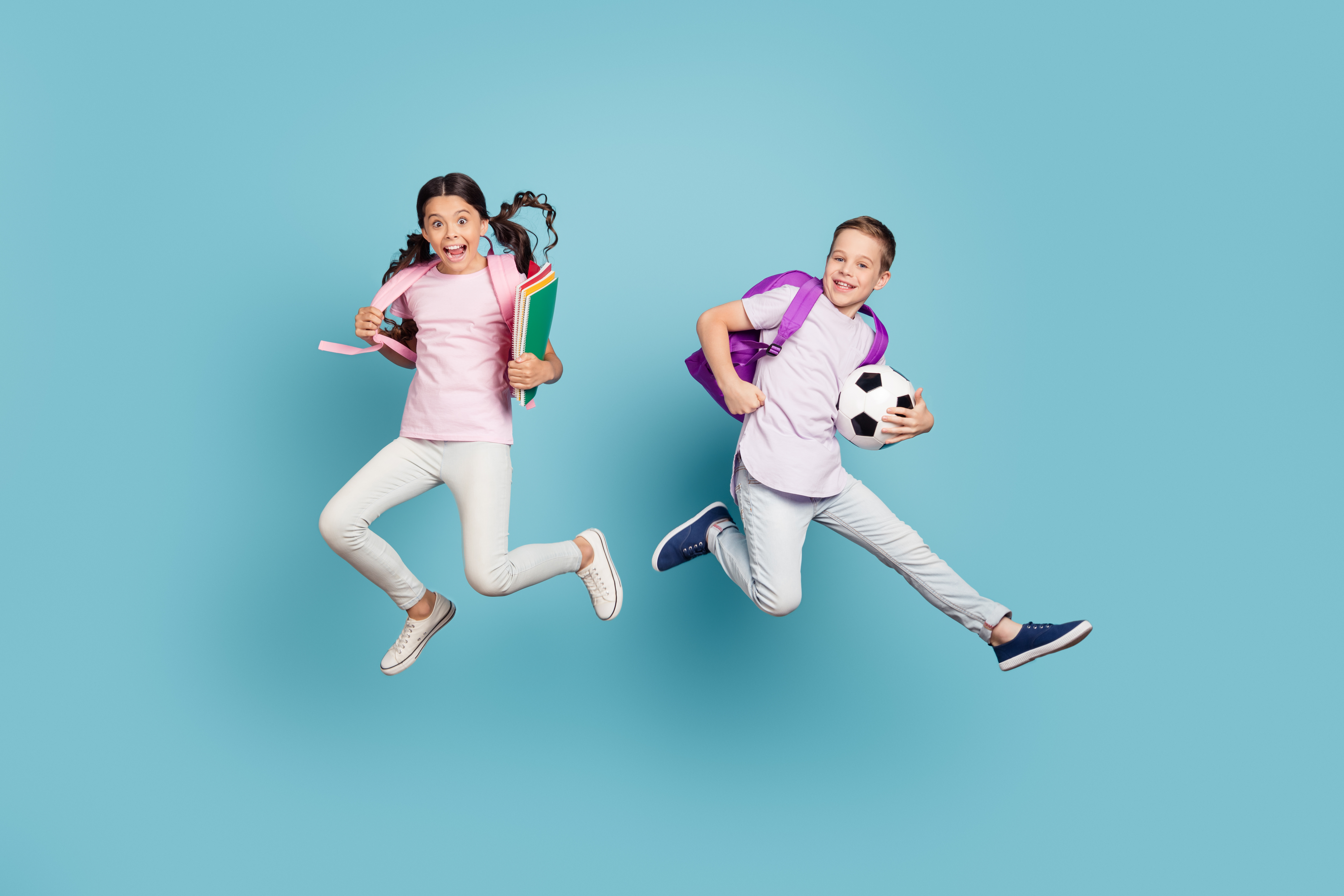 boy and girl jumping with blue background at after school activities